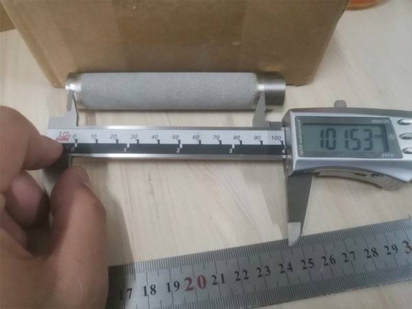 A worker measuring length of porous stainless steel sintered filter element with vernier caliper